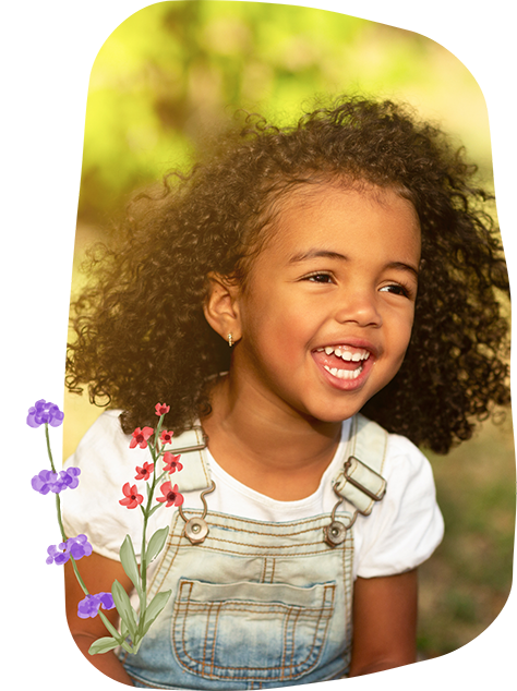 Young girl in overalls smiling outdoors