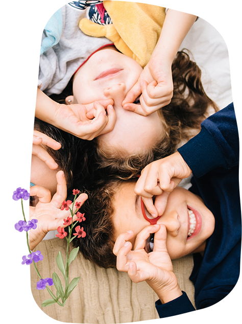Three smiling kids making glasses shapes around their eyes with their hands