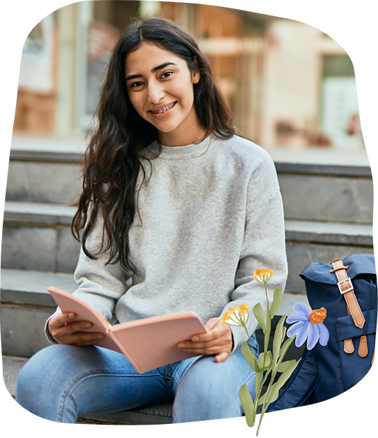Smiling teenage girl holding a book and sitting on a staircase