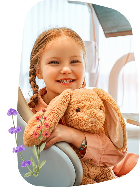 Young girl in the dental chair holding a rabbit plush