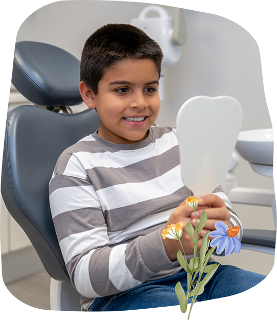 Boy in the dental chair looking at his teeth in a mirror