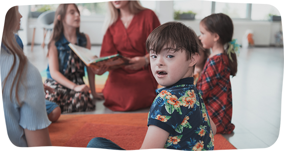 Group of children listening to an adult read a book
